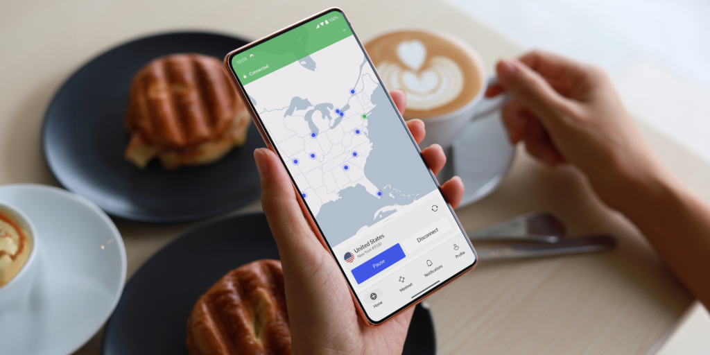 Stock image of a person using NordVPN app while having coffee and pastries