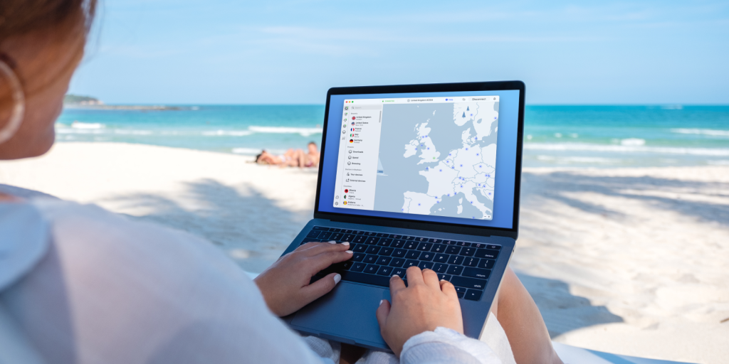 Stock image of woman on the beach with a laptop. Screen shows NordVpn app.