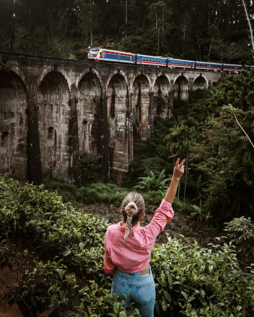 A girl in front of a Nine Arch Bridge in Sri Lanka while the train is passing